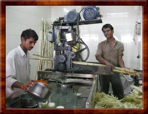 046 Workers making juice crushed from raw sugar cane stock harvested fresh each morning in Pune, India